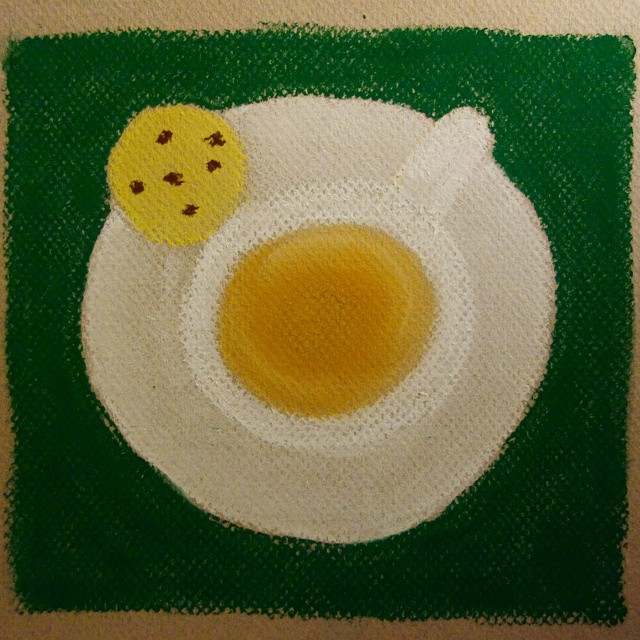 32: Pastel crayon drawing of white teacup and saucer with chocolate chip biscuit on a green background