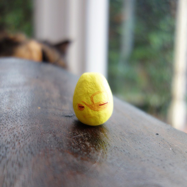 72: A yellow teacup and teapot painted onto a tiny white clay egg