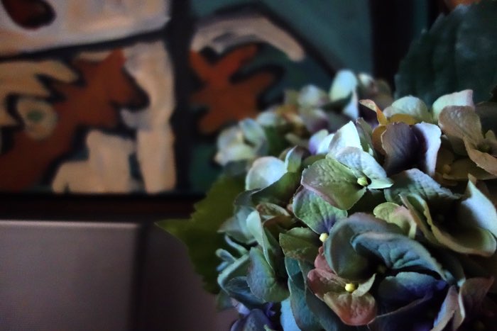 flowers in a vase with a painting in the background